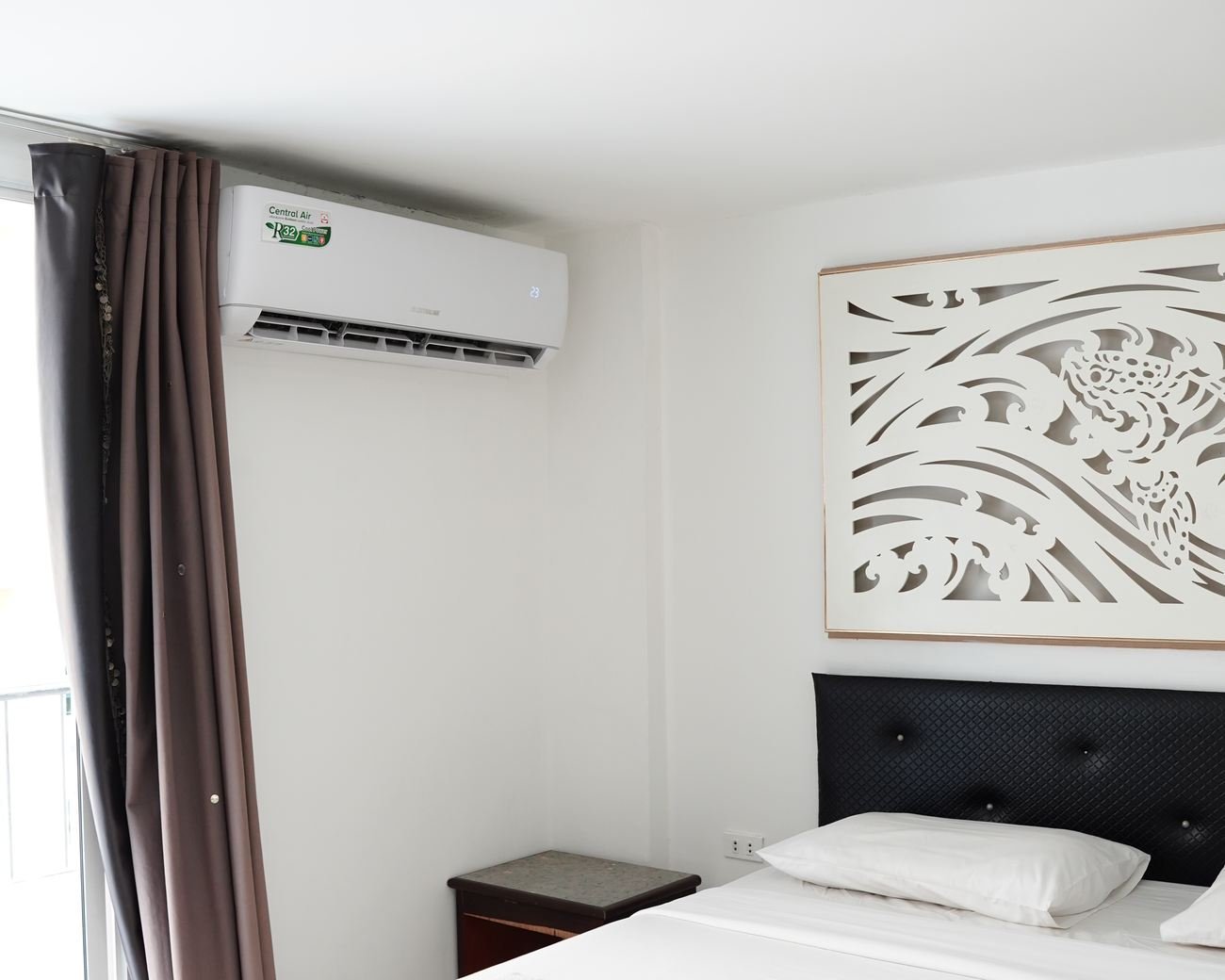 Deluxe room bed with wall-mounted air-conditioning and curtains